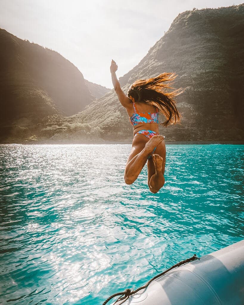 girl jumping off a boat in kauai hawaii's napali coast