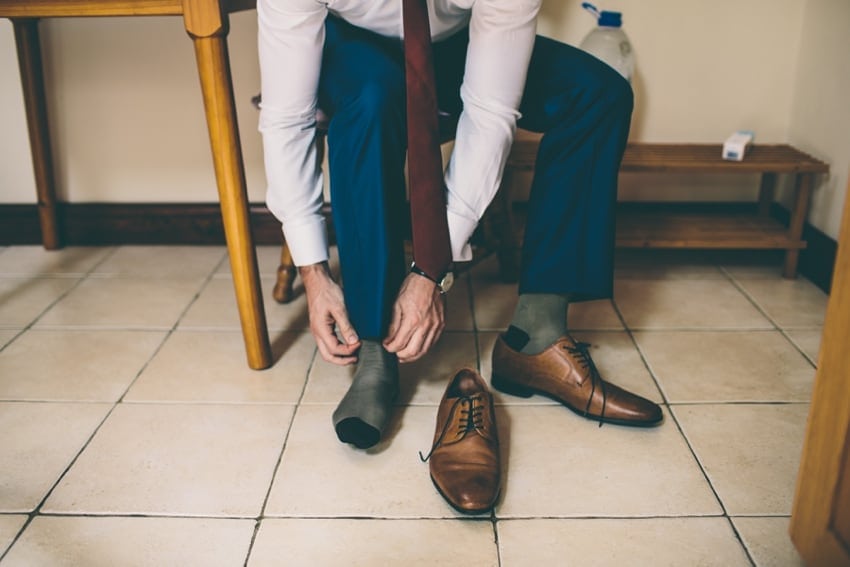 Groom tying brown wedding shoes