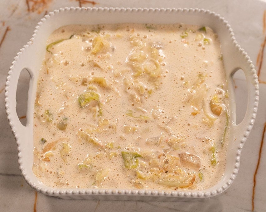 cabbage casserole sauce overlay in a white casserole pan on a marbled background