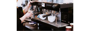 A barista steaming milk on a traditional coffee machine