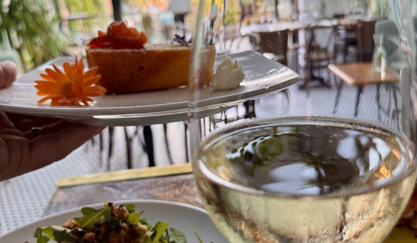 Delicious dessert, fresh salad, and glass of white wine in a charming garden setting.