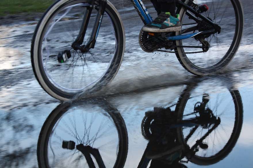 A pair of bicycle wheels slicing through a deep puddle