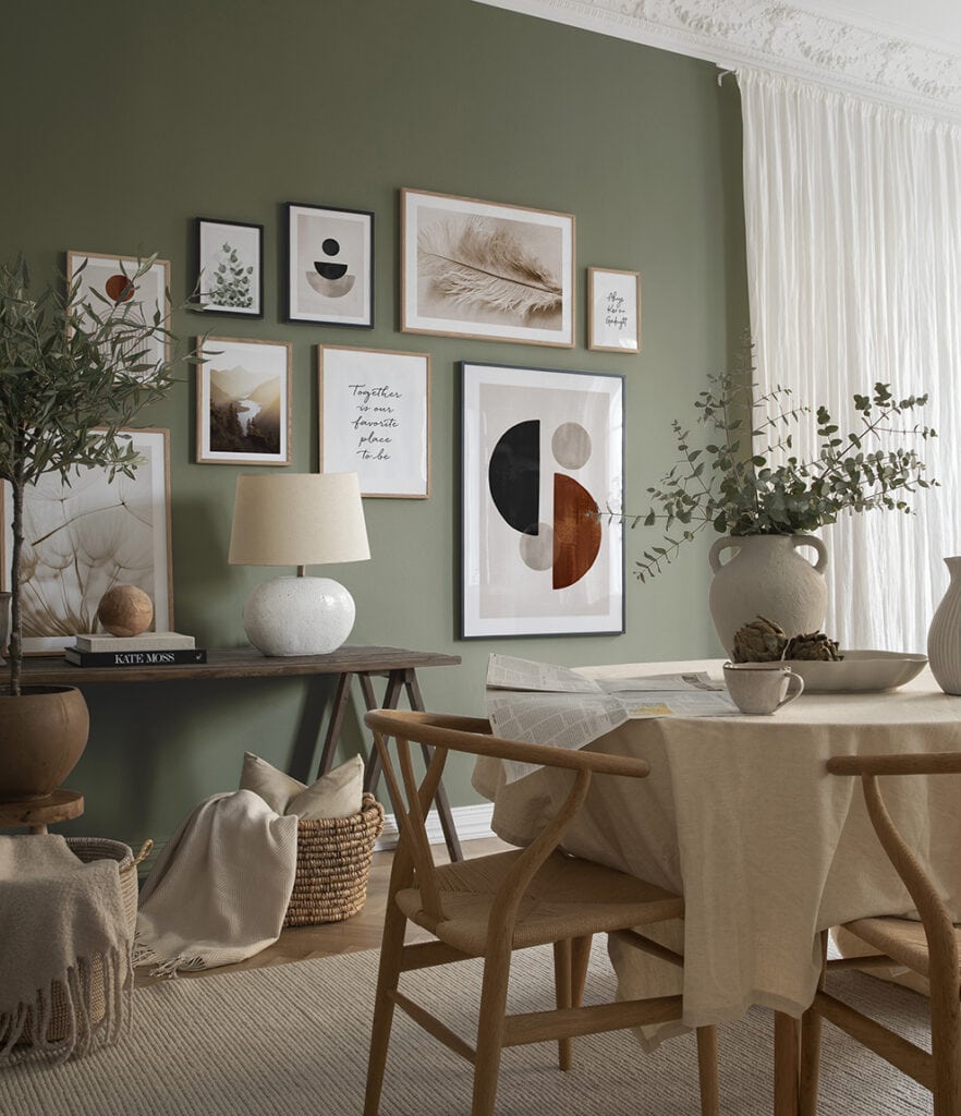 Sala da pranzo in stile scandi, con parete verde salvia e sedie in legno e parete di quadri astratti