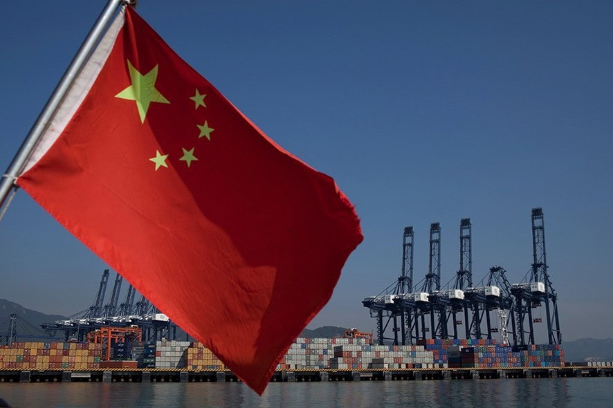 SHENZHEN, CHINA - NOVEMBER 28: A Chinese flag attached to the back of a boat flaps in the wind as cargo containers sit on the dock of Shenzhen Port on November 28, 2010 in Shenzhen, China. According to the US Commercial Service, Shenzhen is one of the fastest growing cities in the world. Home of the Shenzhen Stock Exchange and the headquarters of numerous technology companies, the now bustling former fishing village is considered southern China's major financial centre. (Photo by Daniel Berehulak/Getty Images)