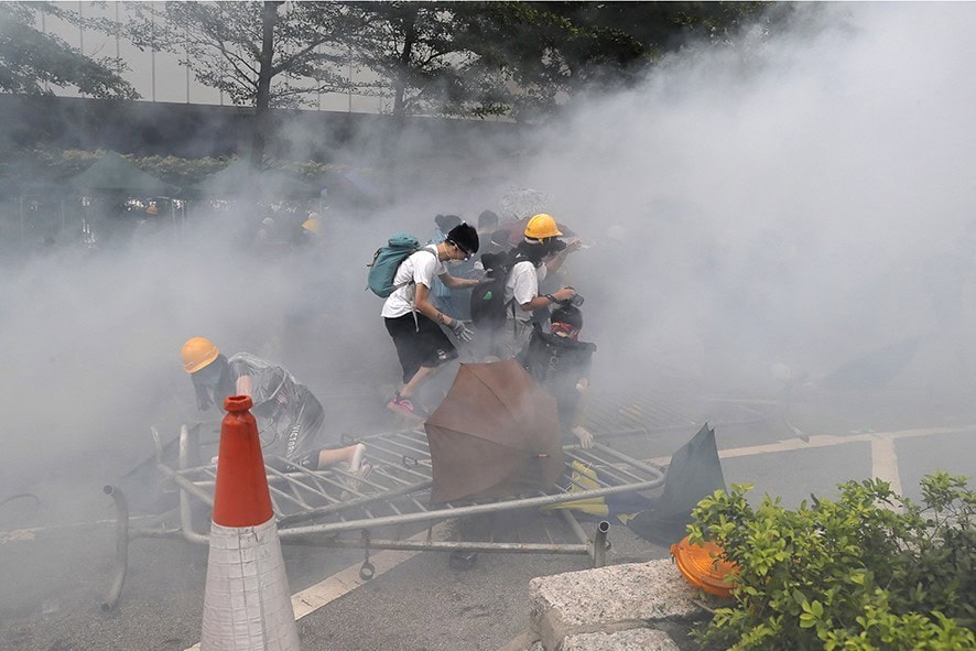 Protestors react to a cloud of tear gas near the Legislative Council in Hong Kong, Wednesday, June 12, 2019. Thousands of protesters blocked entry to Hong Kong's government headquarters Wednesday, delaying a legislative session on a proposed extradition bill that has become a lightning rod for concerns over greater Chinese control and erosion of civil liberties in the semiautonomous territory. (AP Photo/Kin Cheung)