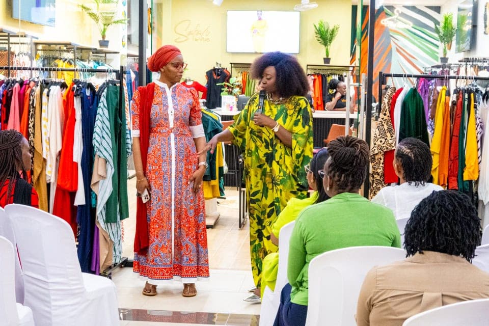 Connie Oluoch presents a patterned outfit beside a model while guests watch at Style, Shop & Sip.