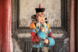 Mongolija putovanje: mlada žena u svečanoj mongolskoj nošnji ispred rezbarenih hramskih vrata