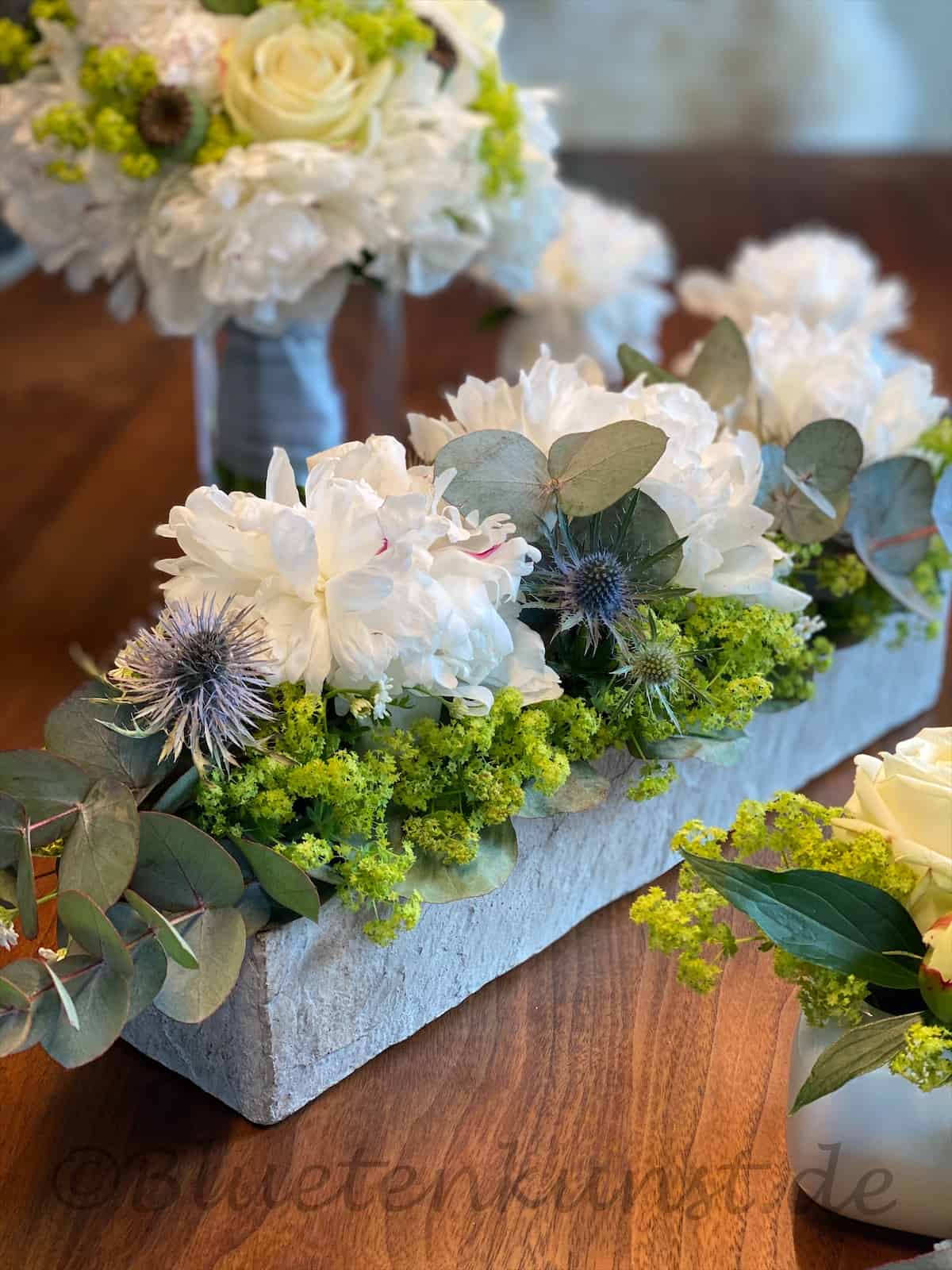 Edle weiße Tischdekoration für Hochzeit edle Pfingstrose in weiß mit Eucalypthus und Frauenmantel, Distel Mannstreu blau
