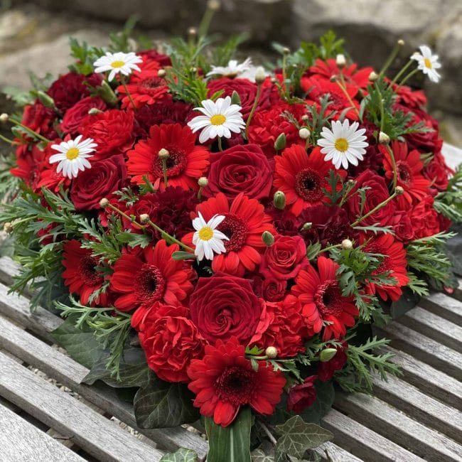 Trauergesteck Herz in rot mit Rosen und gebera und weißer kamile