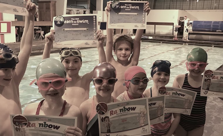 Small group of children proudly showing their swimming badges