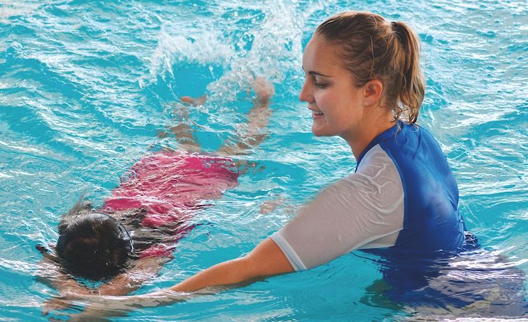 private swimming lesson at home with instructor teaching child in pool