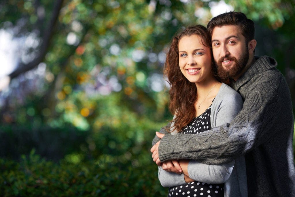 Smiling couple embracing outdoors, symbolizing dating safety and feeling secure in a relationship.