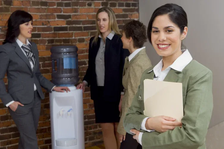 businesswoman smiling in front of team talking at water cooler