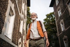 Senior man on the street. Elderly cool man listening to music outdoors, having fun. Concept of old