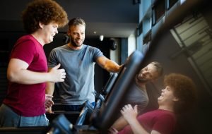 Fat young men with trainer exercising at fitness gym