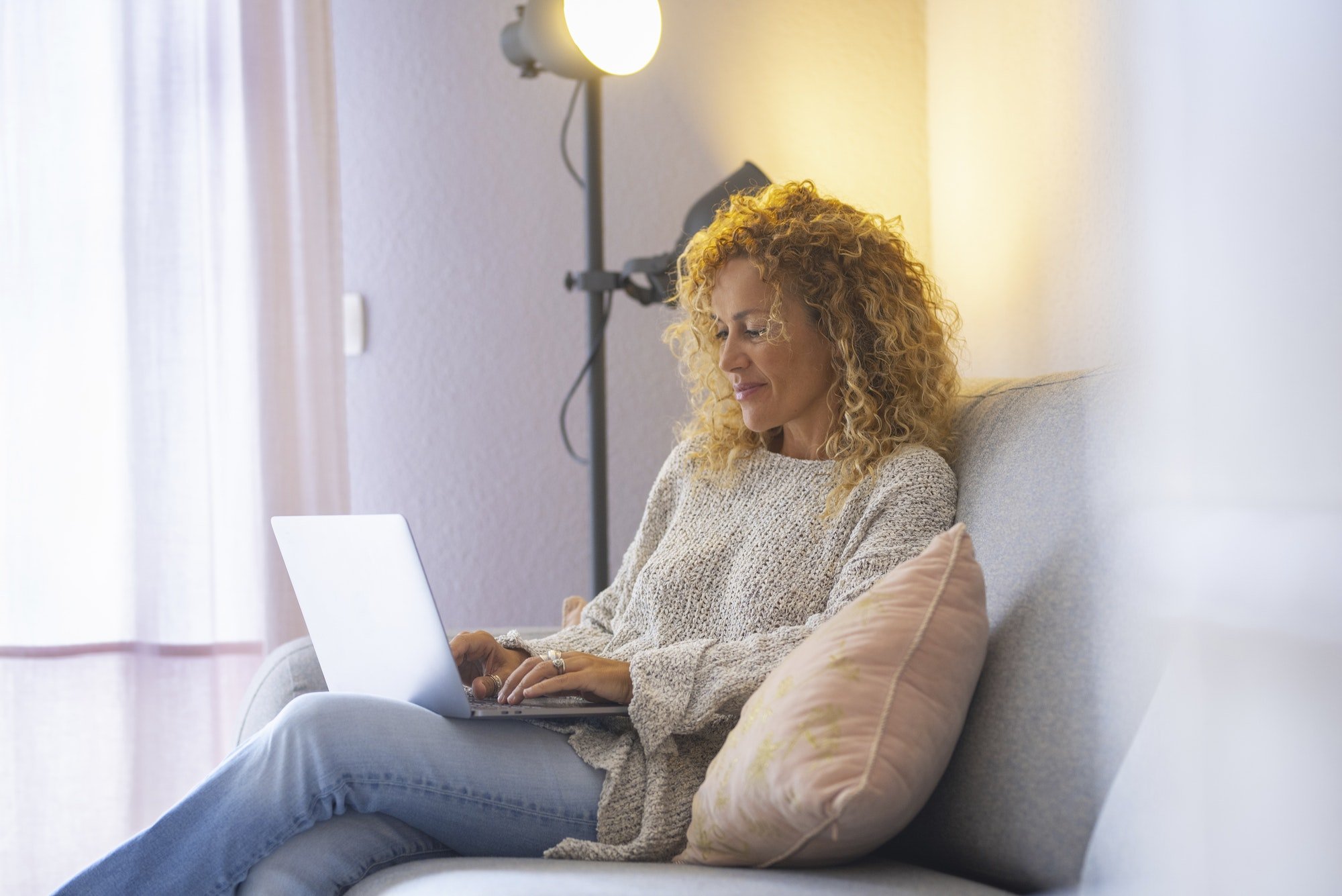 Relaxed and happy adult attractive woman working at home with laptop computer