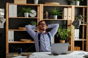 Relaxed happy businessman at work desk cafe table meditating.