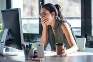 Tired businesswoman yawning while working with computer in the office.