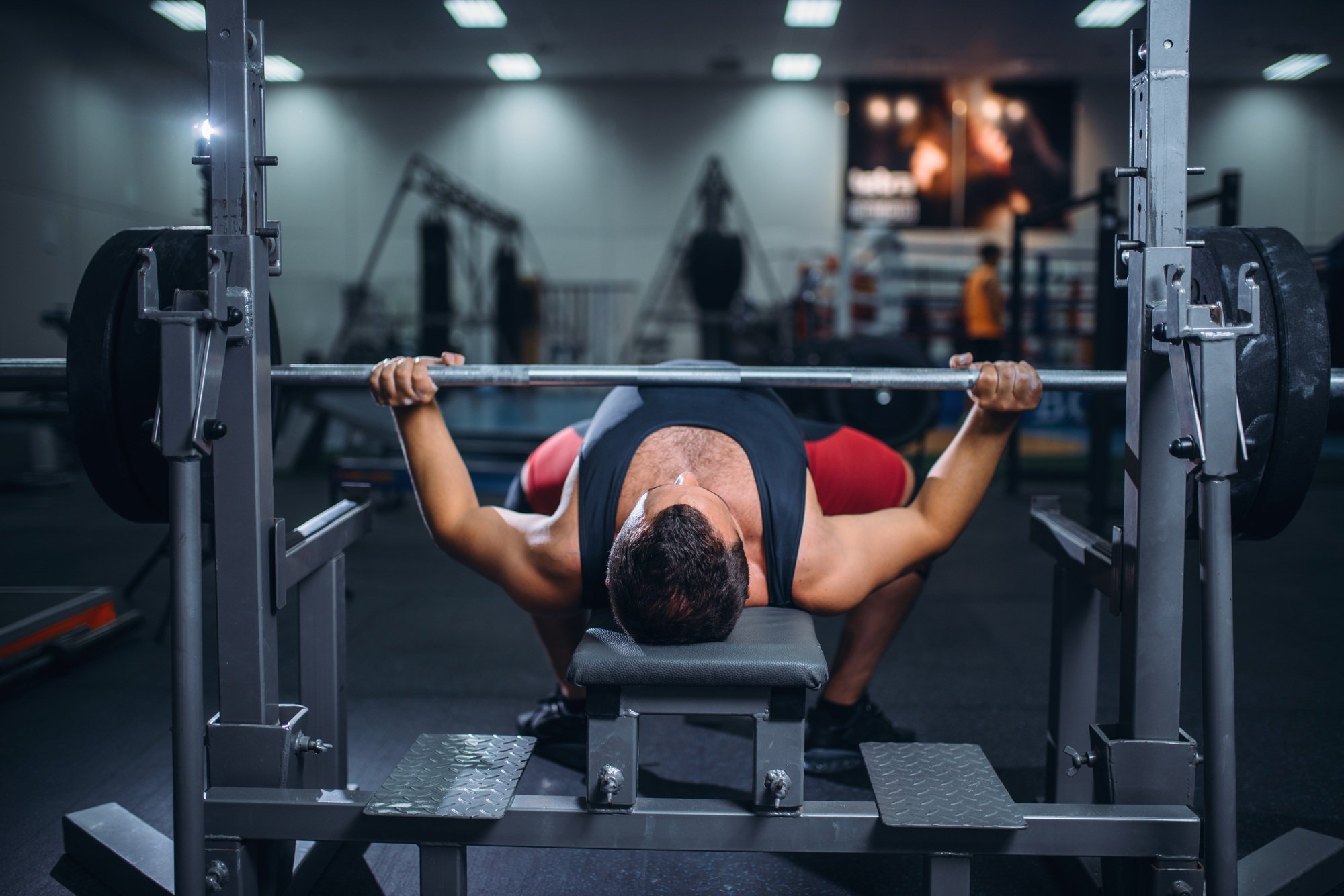 Weight lifter on exercise machine with barbell