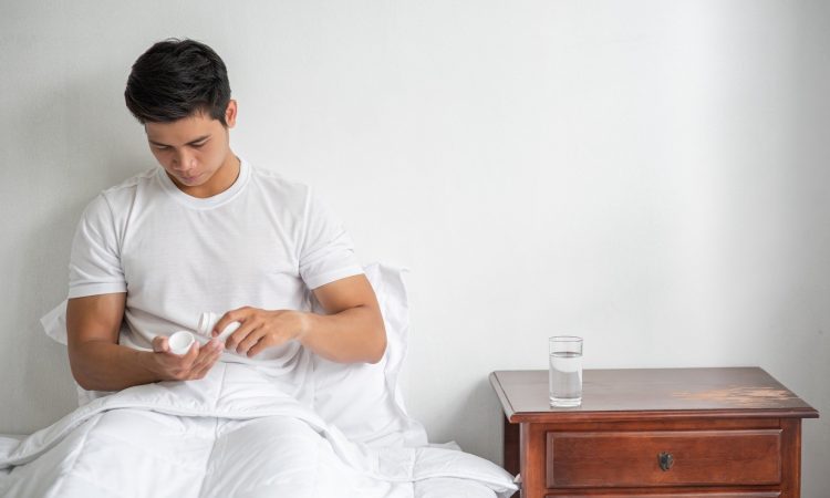 A man who is unwell on the couch and is about to take antibiotics.