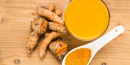 Healthy turmeric roots drinks in a transparent glass on wooden s