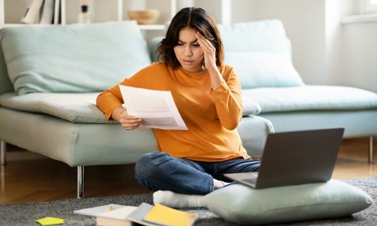Stressed Arab Female Freelancer Working With Papers And Laptop At Home
