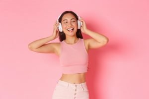 Carefree beautiful asian girl in headphones, dancing with eyes closed and relaxed, happy smile