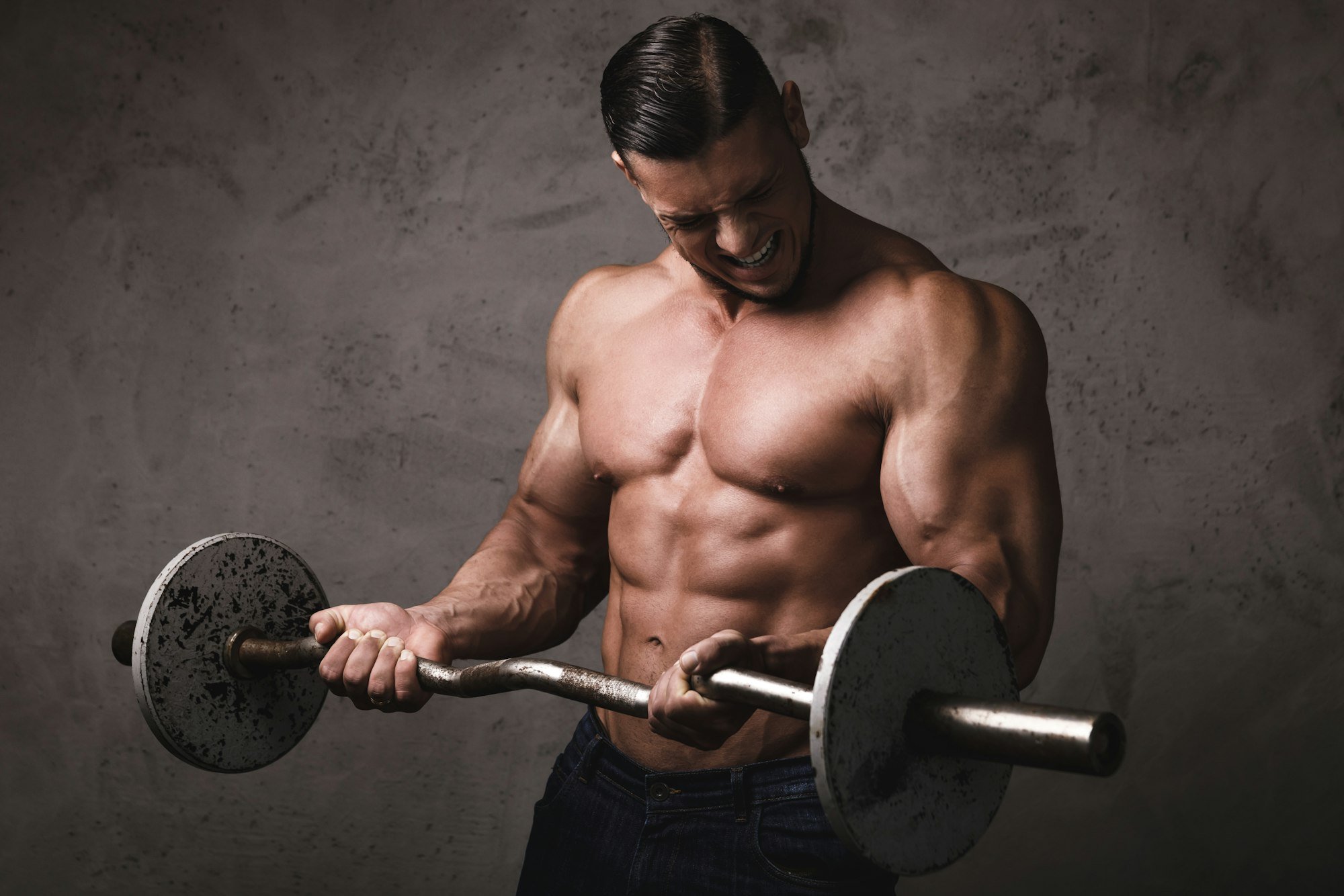 Massive brutal bodybuilder doing exercises with barbell