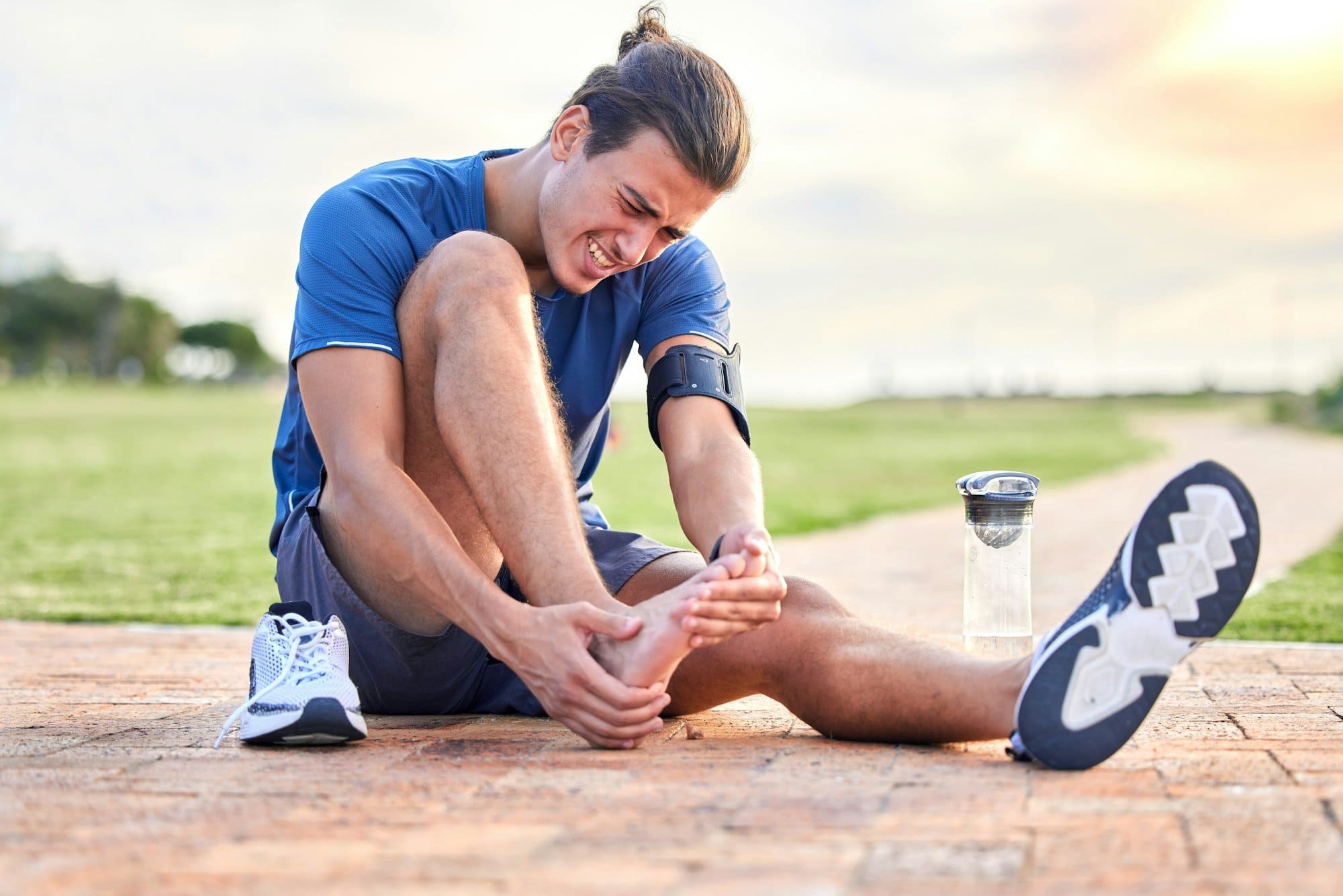 Fitness, injury and foot pain with man in park for muscle spasm, inflammation and joint problem. Ru