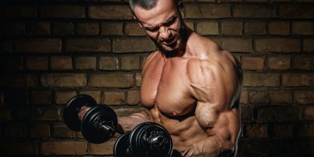 Bodybuilder doing exercises for biceps with a dumbbells