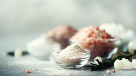 Mix of different salt types on grey concrete background. Sea salts, black and pink Himalayan salt