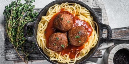 Vegan tomato pasta with plant based Meatballs in a skillet. White background. Top view