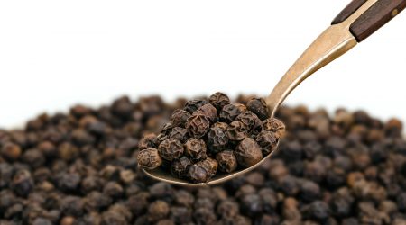 Whole Black Pepper on Old Brass Spoon
