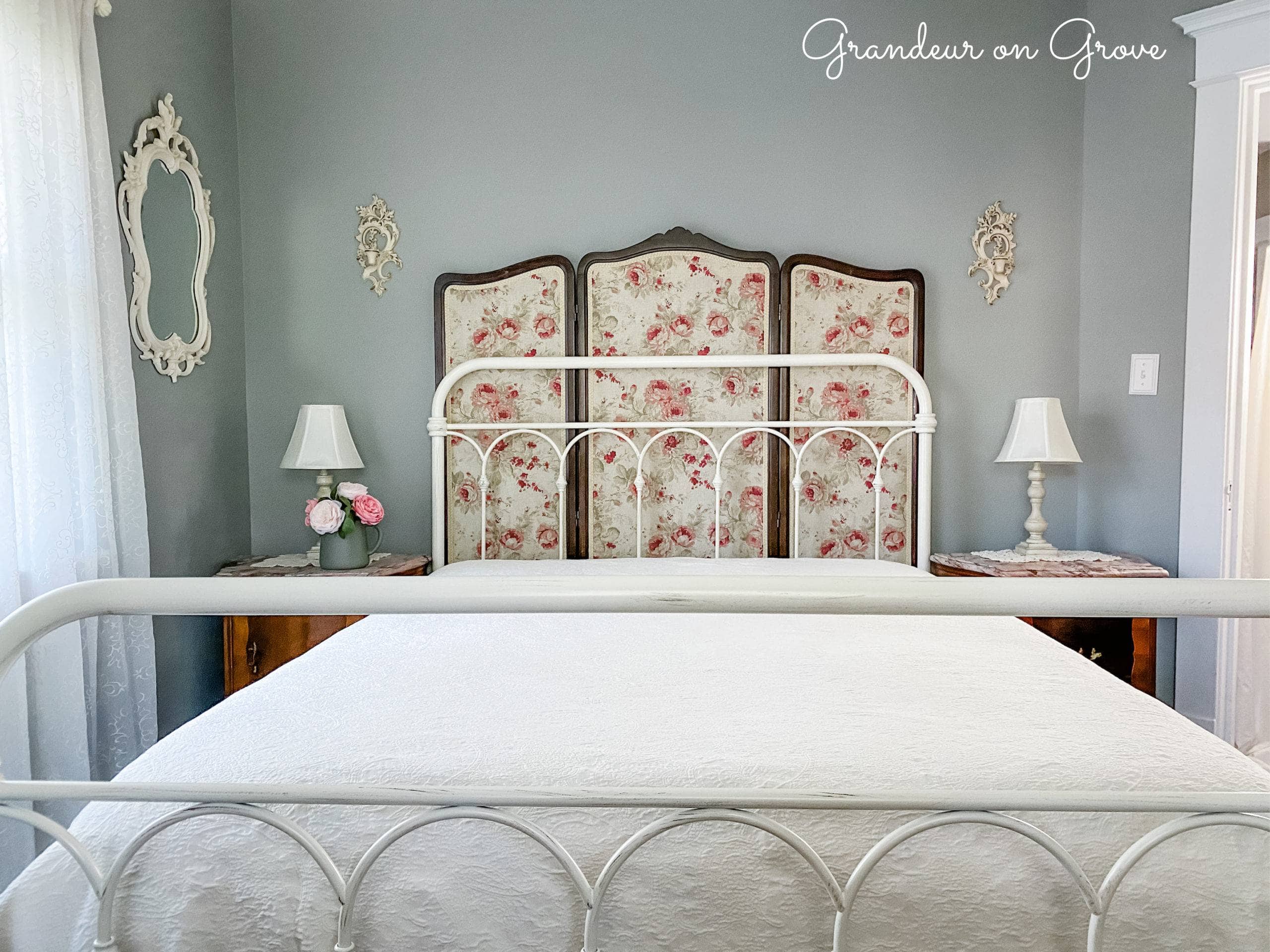 white metal bed frame with rose screen behind