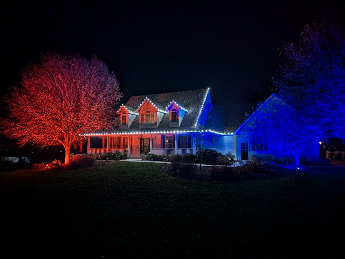 Cape Cod home with dramatic red and blue uplighting on trees