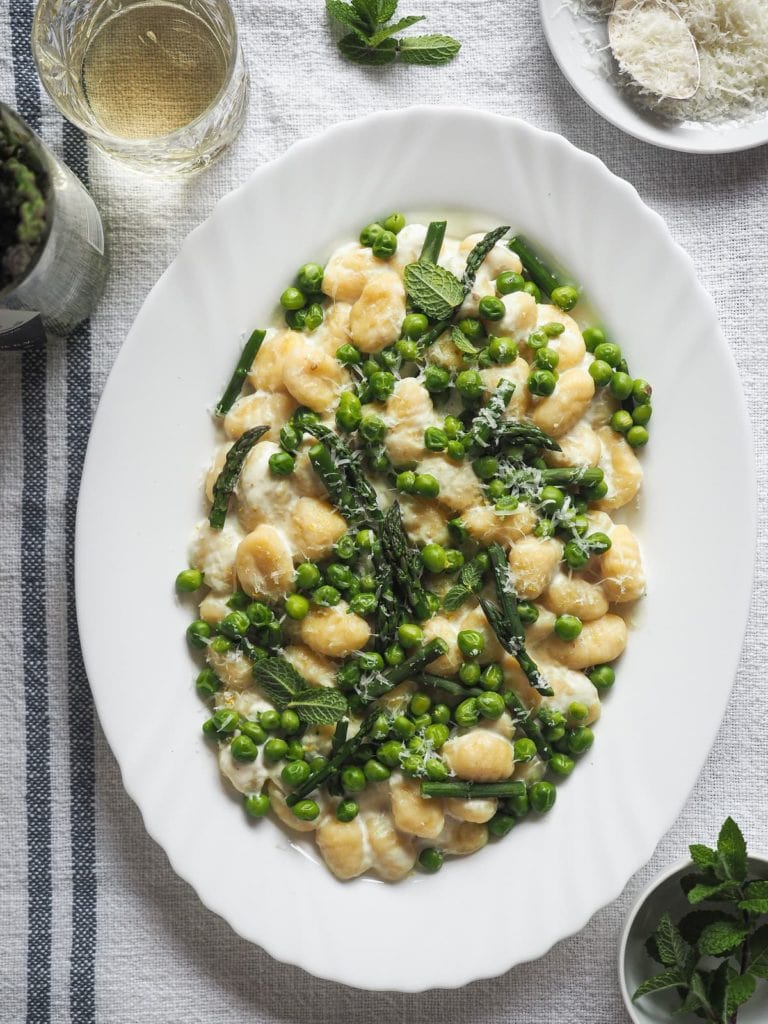 Spring on a plate with these 10-Minute Creamy Gnocchi with Peas and Asparagus. It's really that quick and so delicious! To speed things up I use pre-made gnocchi; then, there are bright peas and asparagus to make the most of seasonal ingredients. These are mixed with a creamy lemony garlicky white sauce that is to die for. And finally, some grated parmesan and mint leaves to top it all. | Paula's Apron Recipe