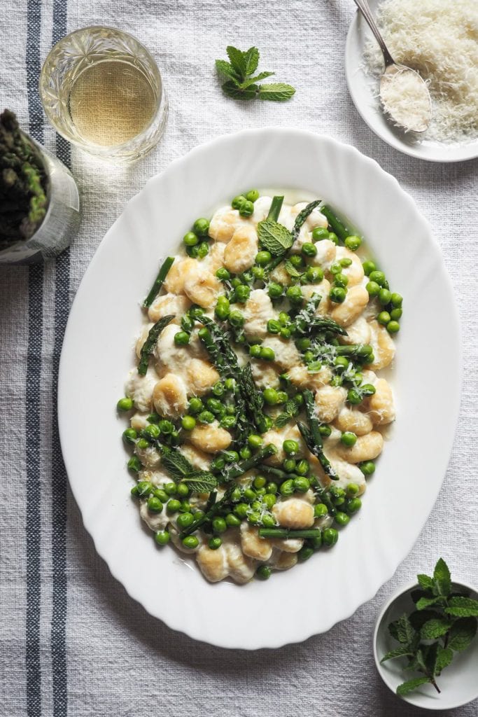 Primavera en un plato con estos Ñoquis Cremosos con Guisantes y Espárragos en 10 minutos. ¡Es un plato tan rápido de hacer y queda tan bueno! Para acelerar las cosas, utilizo ñoquis ya preparados; luego lleva guisantes y espárragos para aprovechar al máximo los ingredientes de temporada. Y por último una salsa cremosa que lleva limón, ajo y crema de leche.¡Simplemente espectacular! Para terminar un poco de menta y queso rallado. | Receta de Paula's Apron