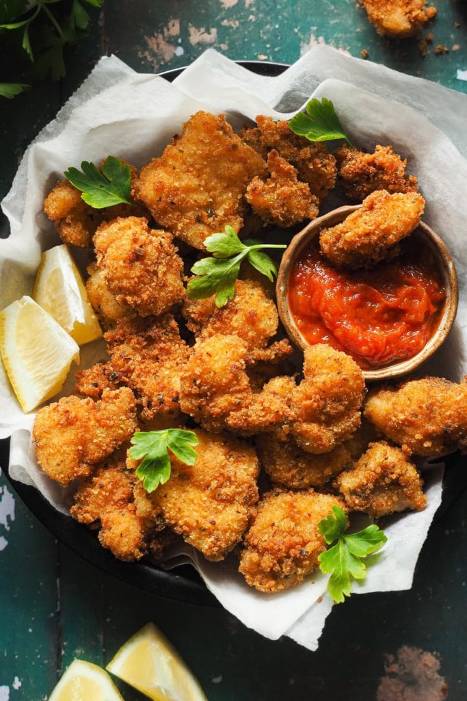 Paula's Apron 15 Minute Fish Nuggets Easy and crispy 15 Minute Fish Nuggets that make an easy kid-friendly dinner, as well as a fabulous appetiser that is sure to be loved by all. In this overhead shot, the golden crispy fish nuggets are served on a plate with parsley leaves on top, a few lemon wedges and a little bowl with tomato sauce. | Receta de Paula's Apron