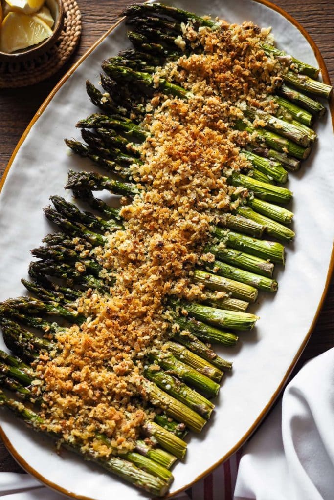 These Garlicky Lemony Crispy Roasted Asparagus are an ideal side dish during spring. Imagine grilled asparagus (because a high-temperature oven cooks them in a similar way :P), but with extra crunchiness and flavour thanks to a garlic, lemon and hazelnut topping! It's perfect to change from classic roasted asparagus, and even those who say they're not the biggest fans of asparagus can't resist these. | Paula's Apron Recipe