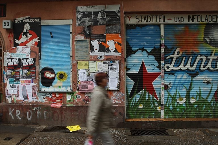 BERLIN, GERMANY - JUNE 21: A woman walks past the radical left-wing and anarchist Die Lunte center in the Schiller-kietz neighborhood in Neukoelln district on June 21, 2012 in Berlin, Germany. Five unknown assailants smashed windows and splashed red paint on the facade of the nearby Schiller Backstube bakery and Schillerbar, and according to media reports a left-wing group protesting rising rents and gentrification of the neighborhood has claimed responsibility. Gentrification, whether real or perceived, of neighborhoods like Neukoelln, Kreuzberg and Friedrichshain has led to threats and violent protests from radical left-wing groups. Berlin, in stark contrast to other European capitals like London and Paris, has long had a very affordable housing market, though prices in central districts have risen dramatically in the last two years. (Photo by Sean Gallup/Getty Images)