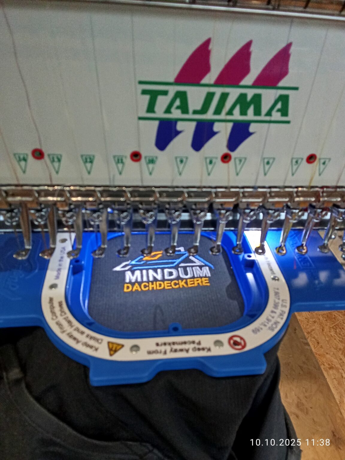 Das Bild zeigt eine Kappe, welche mittels einer professionellen Stickmaschine bestickt wird. 