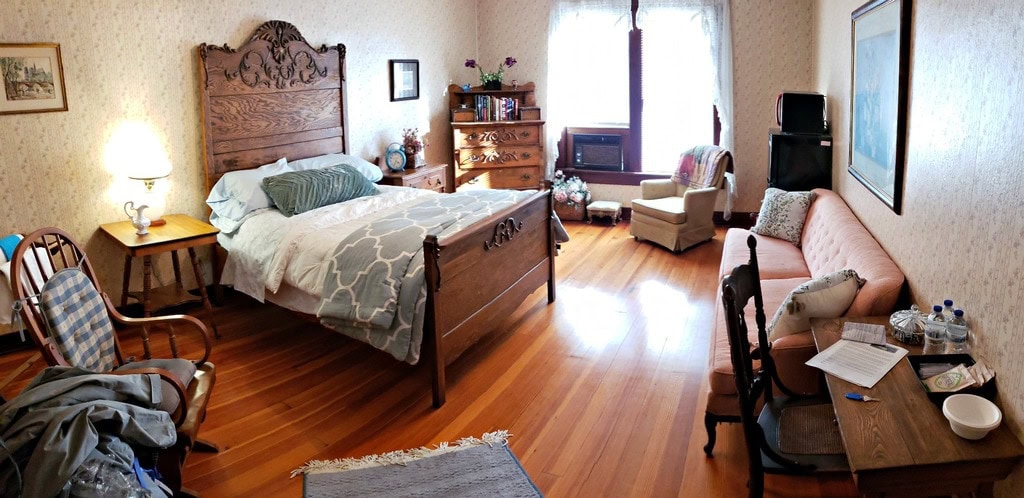 interior of guestroom decorated in Victorian antique furniture, wood floors, sunny window