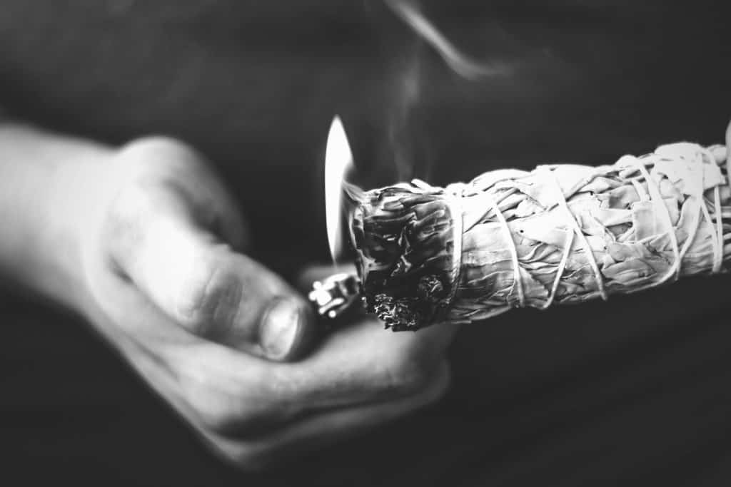 person lighting sage for smudging crystals