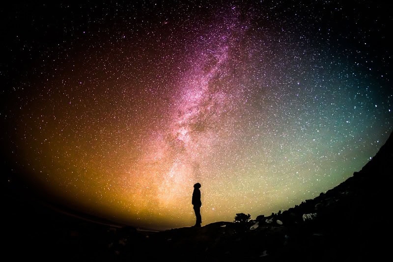 person standing in the universe night sky