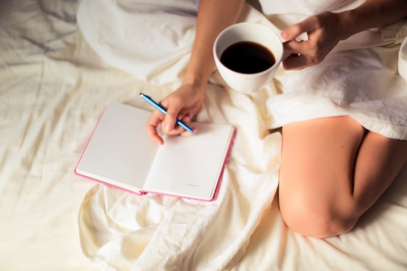 woman writing in journal with coffee