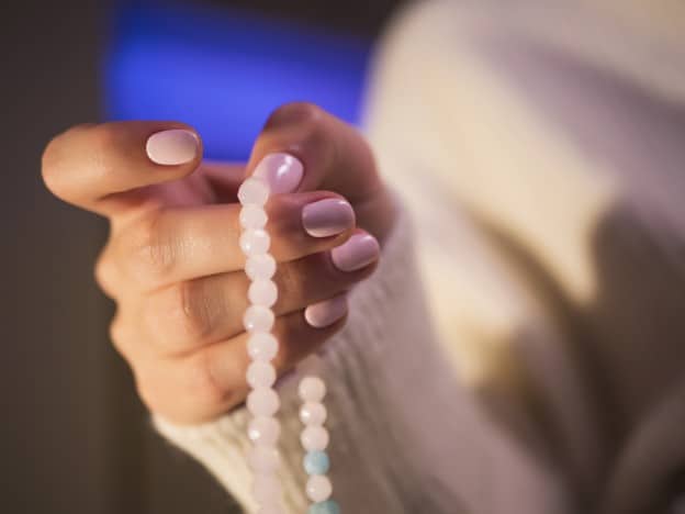 pink mala beads in hand with pink nails