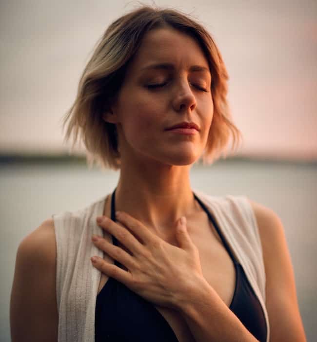 woman holding hand over heart chakra area