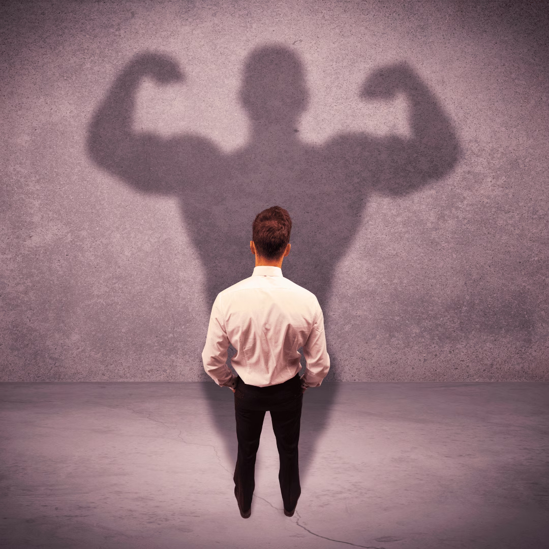 Deine Stärken erkennen und dein wahres Potenzial sichtbar machen Mann erkennt seine Stärken und sieht sein verborgenes Potenzial als starken muskulösen Schatten an der Wand
