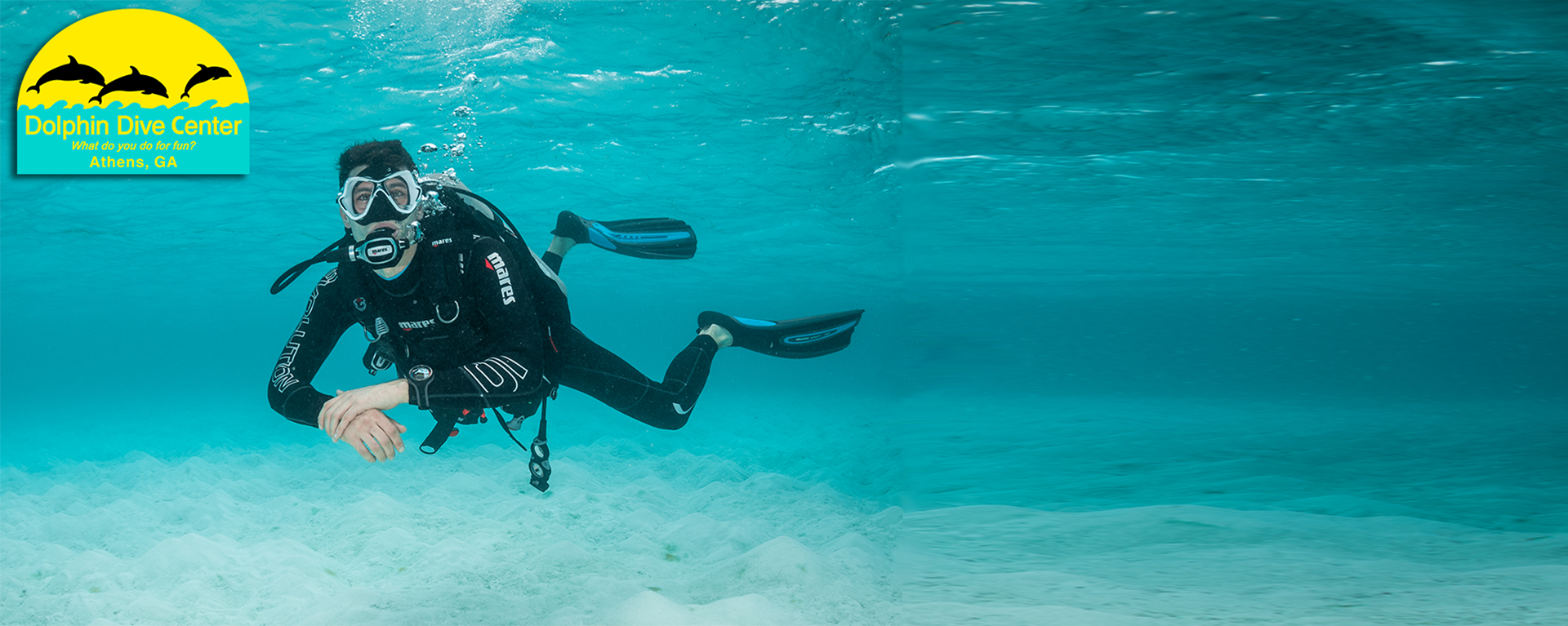 A male scuba diver floating underwater in a pool.
