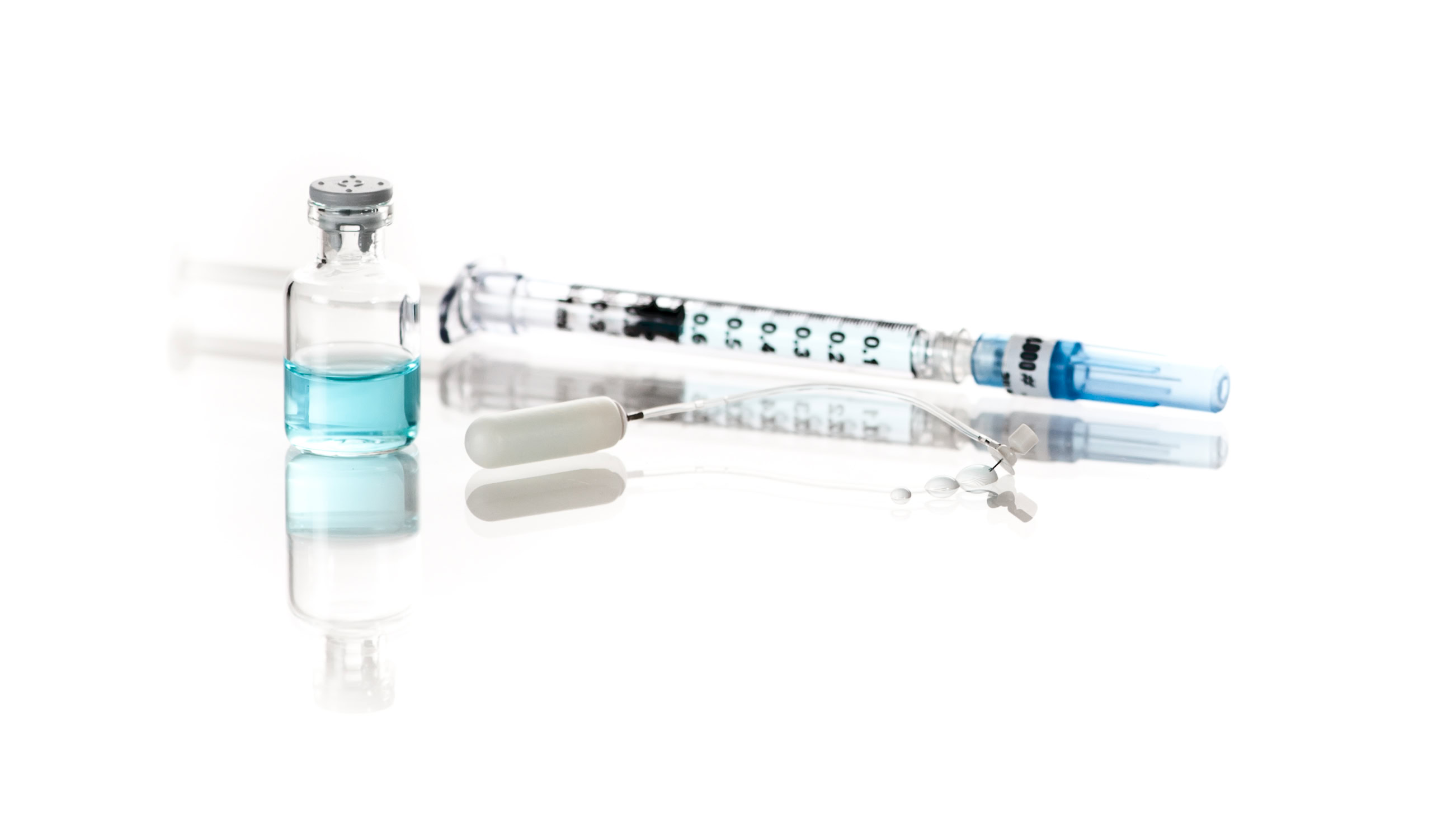 alzet osmotic pump connected to a brain infusion kit with a vial of blue liquid and a syringe in the distance